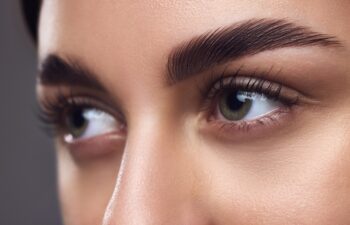 Close-up of a woman's eyes with well-defined eyebrows, full lashes, and smooth skin, highlighting meticulous grooming. Concept of beauty, eyebrow shaping kit, grooming and natural brow look.
