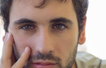Close-up of caucasian boy with beard and clear eyes. Smiling expression Focus on the eyes